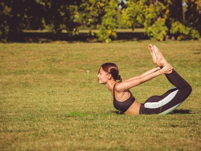 Девушка занимается гимнастикой на зеленой траве