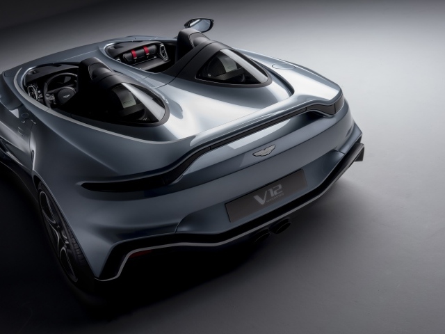 Серебристый автомобиль Aston Martin V12 Speedster 2020 года на сером фоне вид сзади
