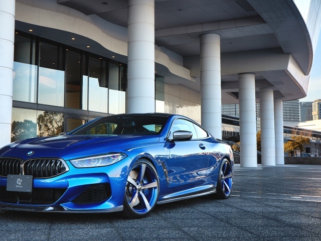 Синий автомобиль BMW M850i XDrive Coupe 2020 года у здания 