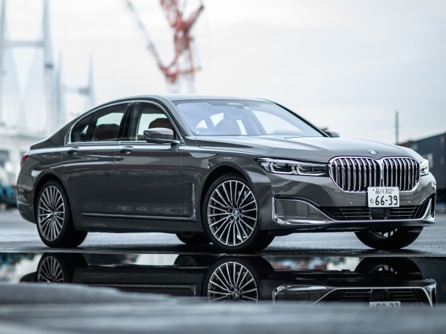 Серебристый автомобиль BMW 745e на мокром асфальте 