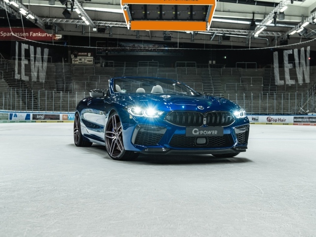 Кабриолет BMW M8,  2020 года с включенными фарами на стадионе 