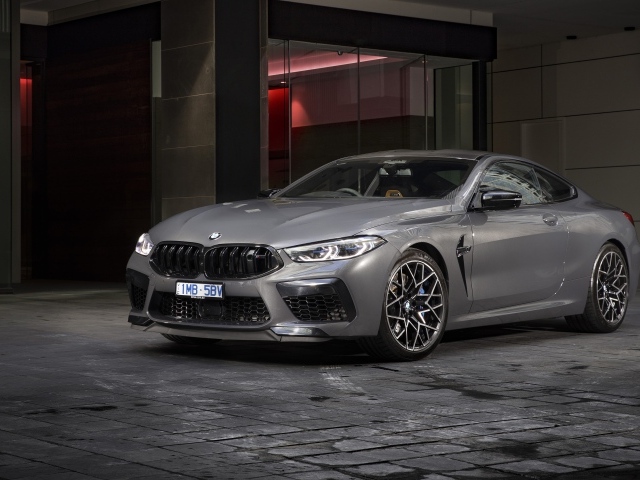 Серебристый автомобиль BMW M8 Competition Coupe 2020 года у здания 