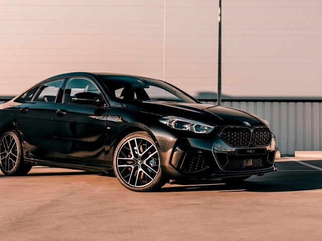 Черный автомобиль BMW M235i XDrive Gran, 2020 года у белого здания 