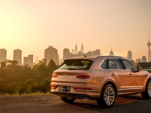 Автомобиль Bentley Bentayga V8 2020 года вид сзади на фоне города 