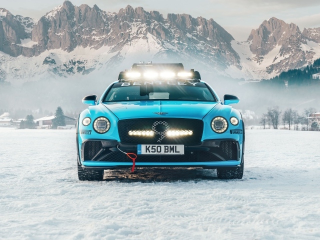 Голубой автомобиль Bentley Continental GT Ice Race 2020 года на фоне заснеженных гор 