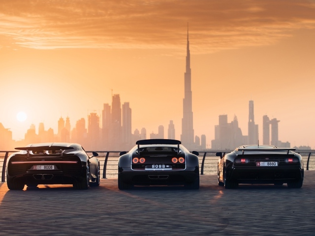 Три автомобиля  Bugatti Veyron и Bugatti Chiron на фоне заката
