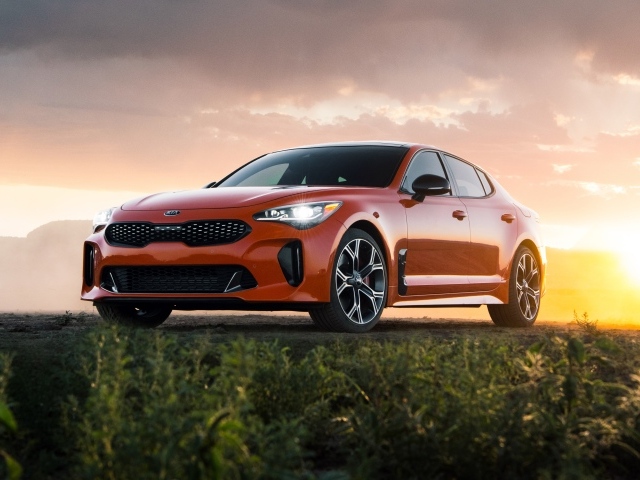 Оранжевый автомобиль  Kia Stinger GTS, 2020 года на закате