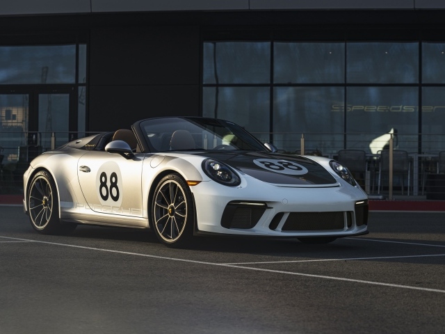 Спортивный автомобиль Porsche 911, 2019 года у стеклянного здания