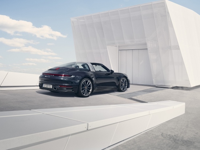 Черный автомобиль Porsche 911 Targa 4S 2020 года у гаража 
