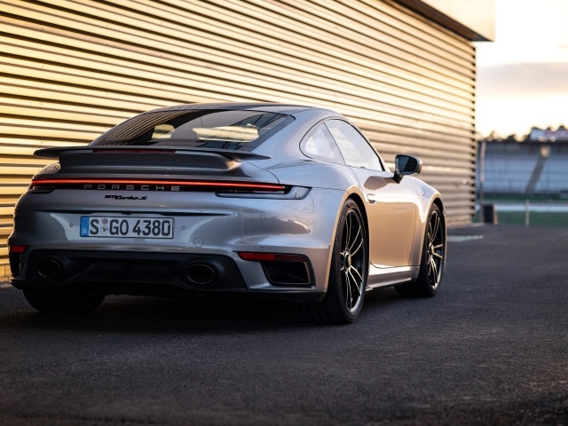 Серебристый автомобиль Porsche 911 Turbo S 2020 года у гаража