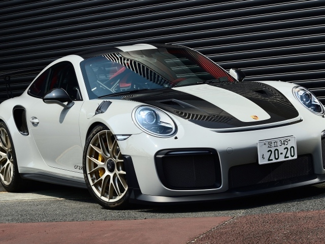 Белый автомобиль Porsche 911 GT2 RS  у черной стены