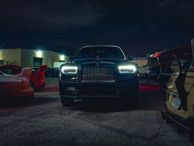 Черный дорогой автомобиль  Rolls-Royce Cullinan, 2020 года с включенными фарами