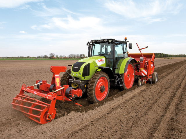 Большой комбайн сеет в поле 