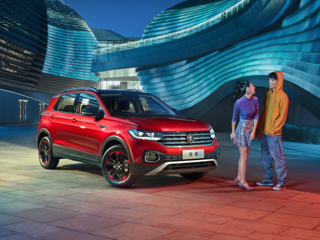 Пара стоит у красного внедорожника Volkswagen Tacqua 280 TSI 2019 