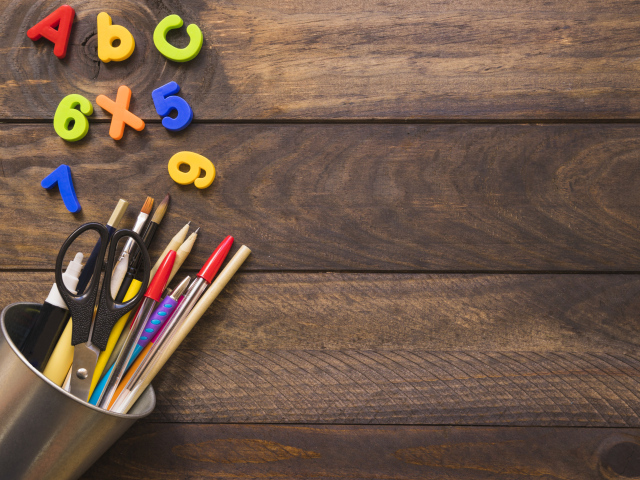 Банка с канцелярскими принадлежностями на деревянном столе с цифрами