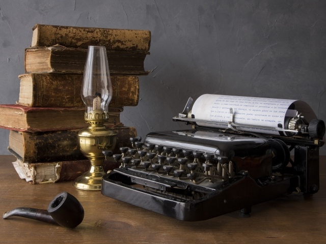 Старая печатная машинка, книги, керосиновая лампа и трубка на столе 