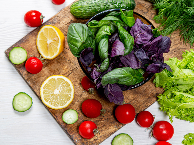 Базилик на столе с зеленью, помидорами и лимоном