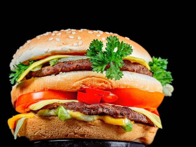 Большой гамбургер с котлетой на черном фоне