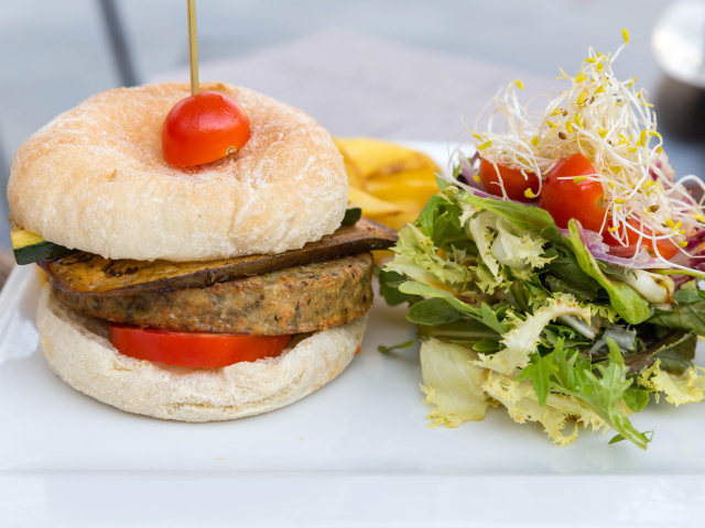 Большой гамбургер с салатом на столе 