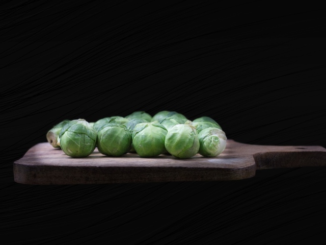 Брюссельская капуста на разделочной доске  на черном фоне