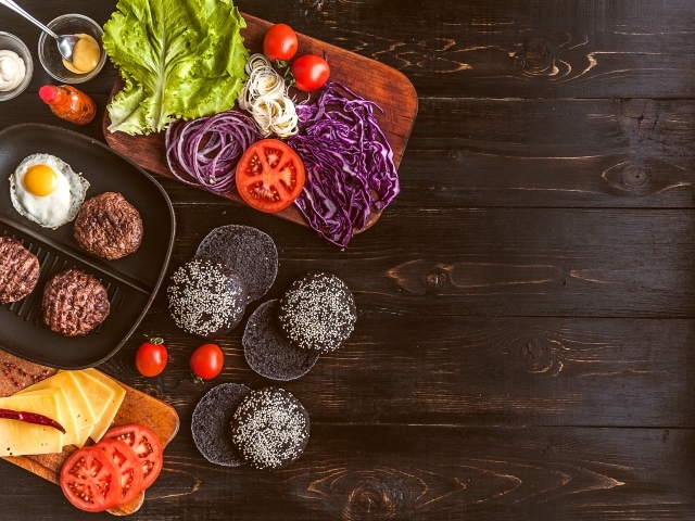 Повар готовит гамбургеры на деревянном столе