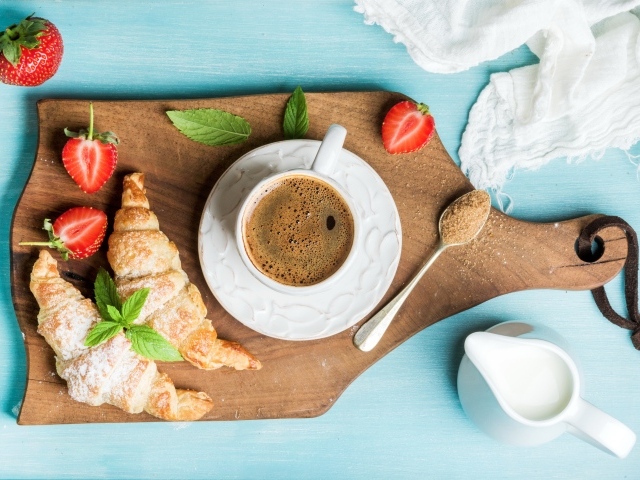 Чашка кофе на доске с клубникой и круассанами