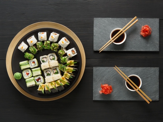 Вкусные  роллы на столе с соевым соусом и палочками 