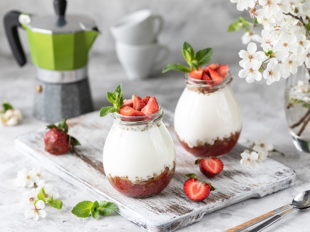 Десерт с йогуртом в банке с клубникой на столе цветами вишни 