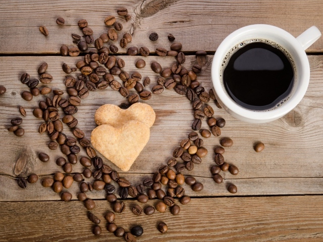 Печенье в форме сердца на столе с зернами и чашкой кофе 