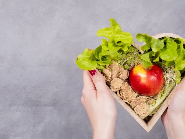 Коробка в форме сердца с яблоком и листьями салата 