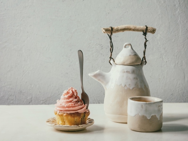 Чайник с чашкой на столе с кексом