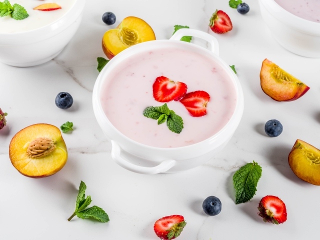 Молочный суп в тарелке на столе с ягодами и нектарином