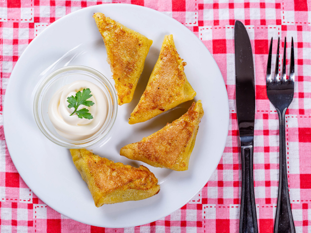 Блинчики со сметаной на столе со столовыми приборами 