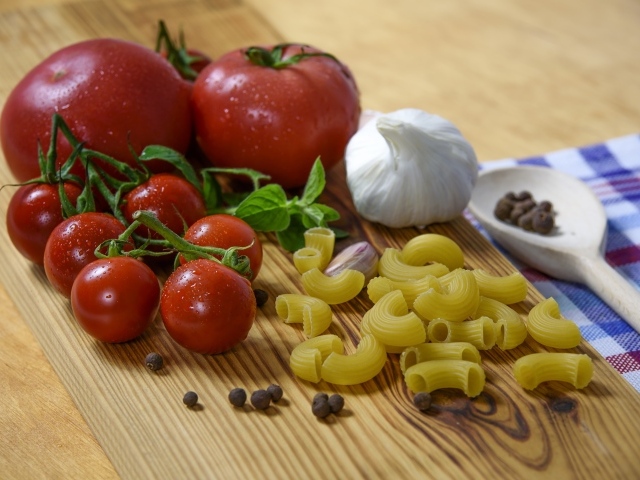 Макароны на столе с помидорами и чесноком