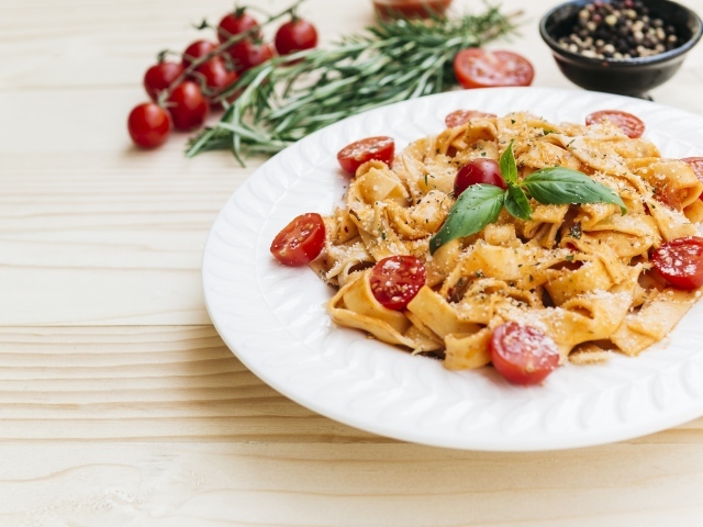 Паста с помидорами черри на белой тарелке