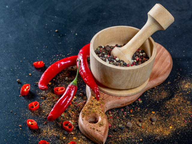 Перец горошком в ступке на столе с острым перцем