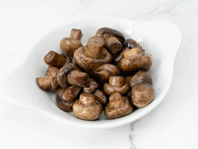 Жареные целые грибы шампиньоны на белом фоне