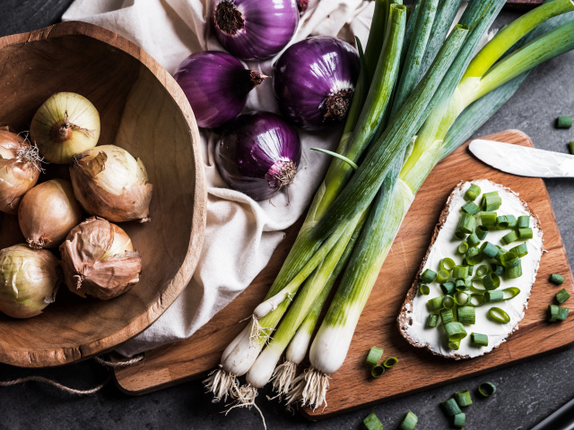 Бутерброд на столе с зеленым и репчатым луком