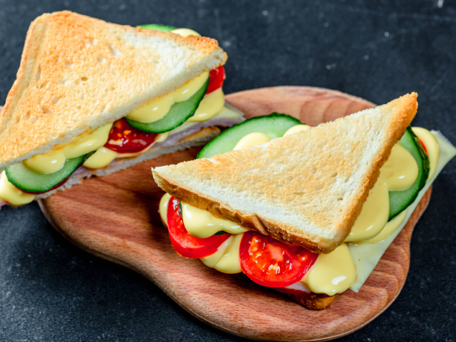 Сэндвич с сыром, помидорами и огурцами на столе