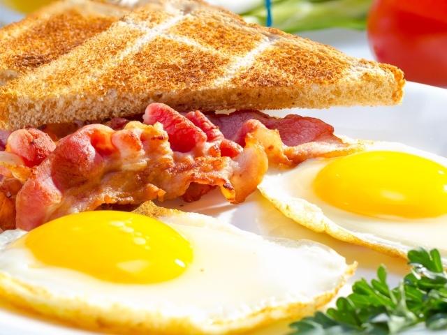 Яичница, бекон и гренки на завтрак на столе 