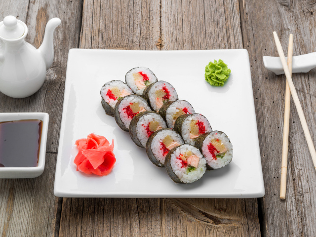 Суши на большой белой тарелке с соусом васаби и имбирем на столе соевым соусом