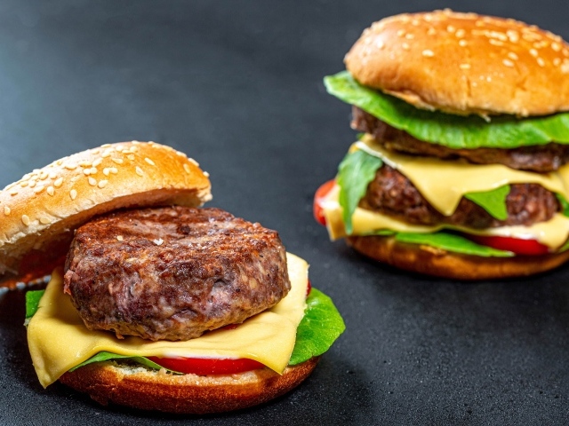 Два аппетитных гамбургера с сочной котлетой на сером фоне
