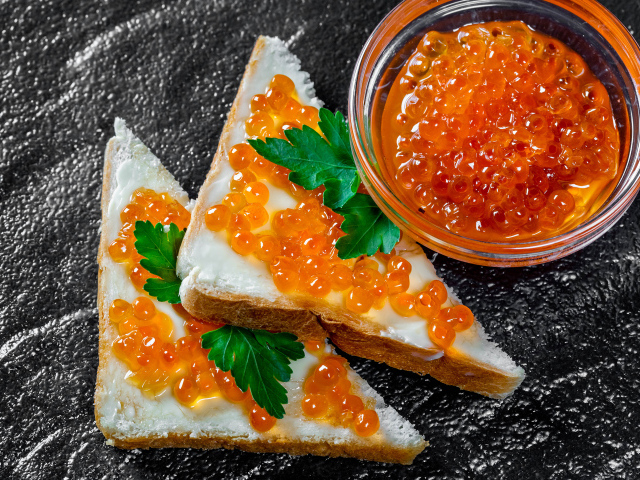 Два бутерброда с красной икрой на столе