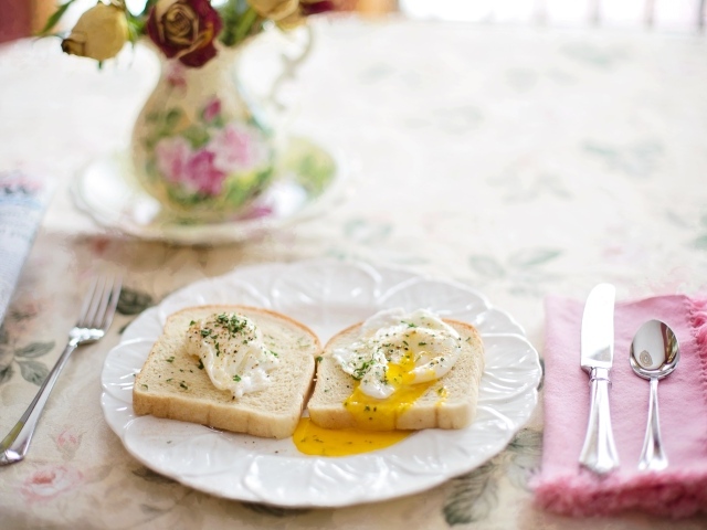 Два куска хлеба с яичницей на белой тарелке на завтрак 