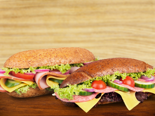 Два вкусных бутерброда с овощами и колбасой на столе 