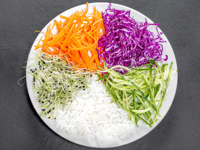 Овощи с рисом на большой  белой тарелке на сером столе 