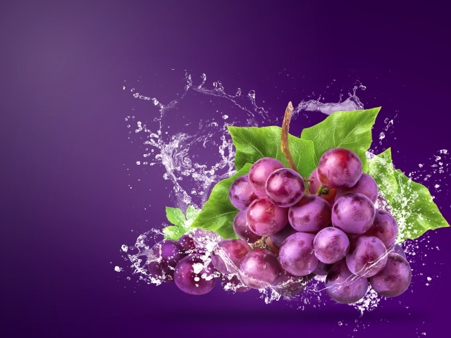 Гроздь розового винограда в брызгах воды на фиолетовом фоне