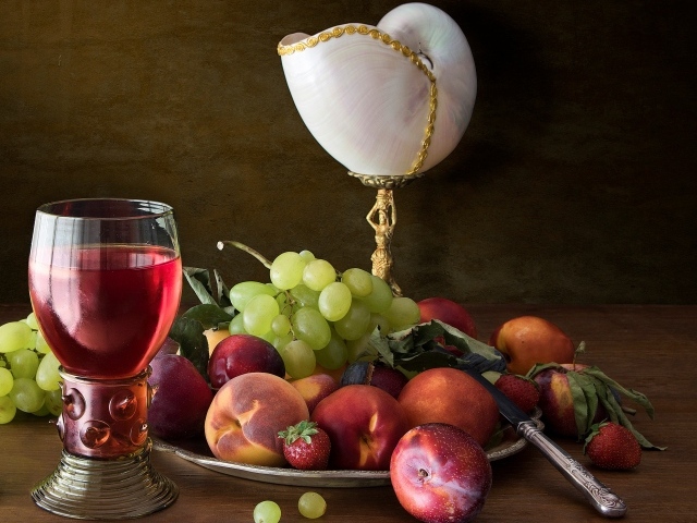 Свежие фрукты и ягоды на столе с вином и лампой 