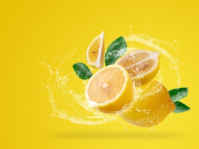Лимоны в брызгах воды на желтом фоне