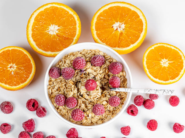 Овсяные хлопья с малиной на белом фоне с апельсинами